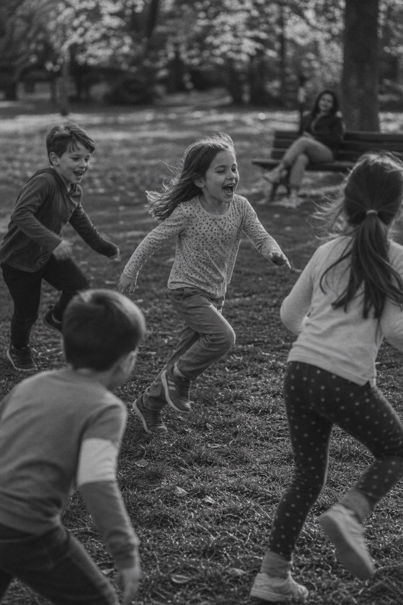 A child mid-run and laughing inside a game of tag, a parent relaxed on a bench in the background